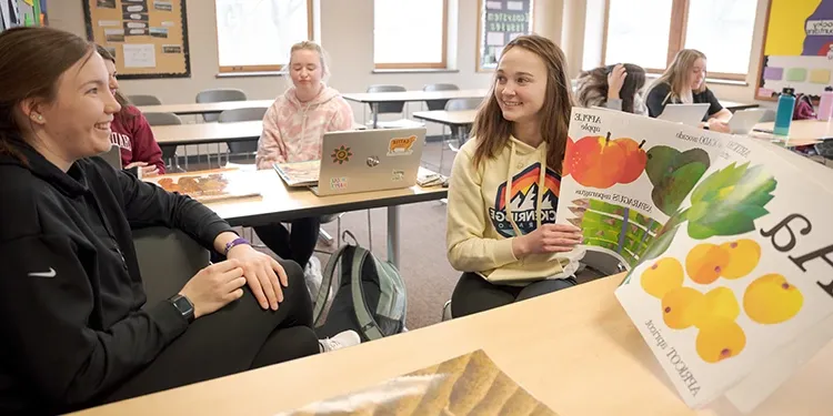 Students in an education class practice reading a large oversized picture book to each other